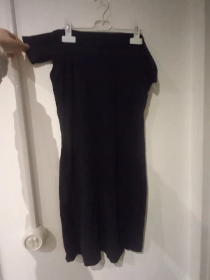 Svart offshoulder klänning Gina Tricot - Säljer en svart, tight offshoulder klänning från Gina Tricot. Klänningen är kort och har en enkel, stilren design som sitter snyggt på kroppen. Perfekt för dig som gillar minimalistisk stil och vill ha något som känns både trendigt och bekvämt.