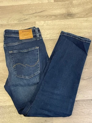 Mörkblå jeans från Jack & Jones - Snygga mörkblå jeans från Jack & Jones med klassisk femficksdesign och kontrastsömmar. Jeansen har en rak passform och är tillverkade i ett mjukt denimtyg som ger en bekväm känsla. Perfekta för en avslappnad och stilren look. Pris går att diskutera 
