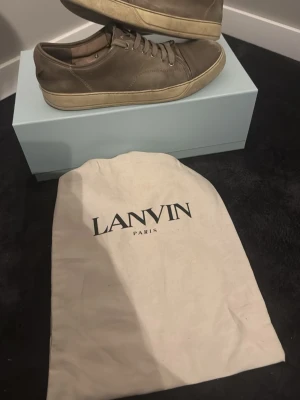 Lanvin - Snygga bruna sneakers från Lanvin i mjukt läder med beige sula och matchande bruna skosnören. Klassisk låg modell med stilren design och diskreta sömmar. Perfekta för dig som gillar exklusiva och tidlösa skor från Paris.