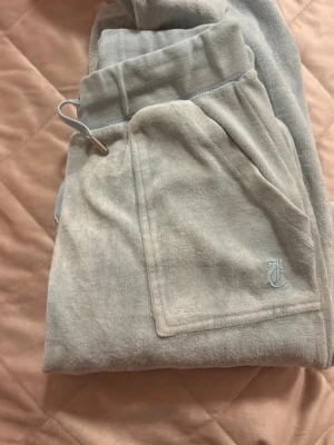 Ljusblå velourbyxor Juicy Couture - Mysiga ljusblå mjukisbyxor från Juicy Couture i mjuk velour. Lite rostiga på bakfickorna se bild tre. Men annars bra skick.