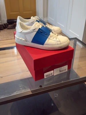 Valentino Garavani vita sneakers blå detalj - Säljer ett par Valentino skor, köpta från merchsweden, storlek 41,5, skorna är i väldigt bra skick även använda ett få tall gånger. MVH Axel