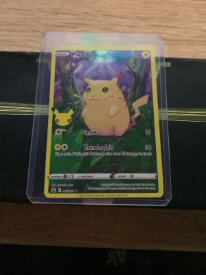 Pikachu Pokémonkort i plastficka - Säljer ett Pikachu Pokémonkort med gul ram och färgglad bakgrund. Kortet är inplastat i en genomskinlig plastficka och har attackerna Gnaw och Thunder Jolt. Perfekt för samlare eller Pokémonfans.
