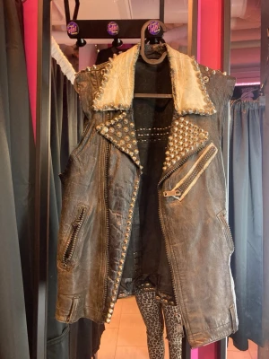 Black leather punk vest - Musta niititetty liivi. N. Kökkö M. Paljon elämää nähnyt. Niittejä puuttuu ja vetoketju rikki.