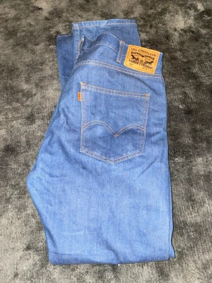 Blå Levi's jeans med orange detalj 505 - Snygga blå jeans från Levi's med orange etikett istället för den vanliga röda som gör dessa speciella. Väldigt fina och aldrig använt dessa. Storlek är W38 L34