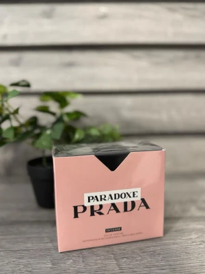 Prada Paradoxe Intense parfym - Prada Paradoxe Intense är en exklusiv parfym i en elegant, ljusrosa kartong med svart detalj upptill. Förpackningen har en modern och stilren design med tydlig Prada-logga. Perfekt för dig som vill ha en lyxig doftupplevelse från ett välkänt modehus.