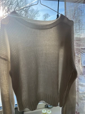 Vit ribbstickad tröja - Säljer en vit ribbstickad tröja med lång ärm och rund halsringning. Tröjan har en croppad passform och är tillverkad i ett tunt, mjukt material som ger en avslappnad look. Perfekt att styla med höga jeans eller kjol.