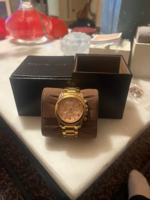 Guldig klocka från Michael Kors - Snygg guldig klocka från Michael Kors med metallarmband och detaljerad urtavla. Klockan har flera små urtavlor och klassisk rund form. Perfekt accessoar för dig som vill sticka ut med stil. Pris kan diskuteras.