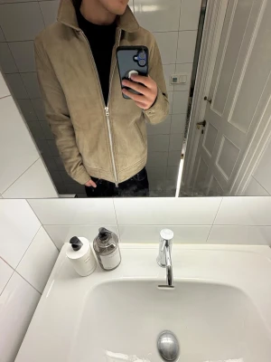 Beige Mocka Jacka HS - Säljer en beige mockajacka (Modell: Alfons) från Human Scales i storlek M. Jackan är väldigt trendig och har använts flitigt, vilket också syns på skicket (därav priset)  Det finns vissa defekter: – På bild 5 syns mörkare partier i mockan på insidan. – På bild 6 syns ett hål i det blå fodret på insidan.  I övrigt är jackan i helt okej skick för att vara välanvänd. Tänk på att den väger lite mer än en vanlig jacka på grund av mockamaterialet 💪💪 INKÖPT FÖR 3000kr