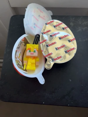 Kinderägg Minecraft-figur gul - Säljer en gul Minecraft-inspirerad nyckelring från Kinder. Figuren är tillverkad i syntetmaterial och har en pixel-design med gröna ögon och orange detaljer. Perfekt som accessoar till väskan eller nycklarna. Medföljer choklad helt stängd.