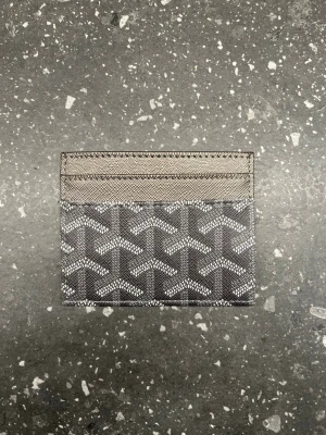 Grå korthållare - Snygg korthållare i grått med det klassiska mönstret och diskret logga på framsidan. Plånboken har flera kortfack och är tillverkad i canvas med läderdetaljer. Perfekt för dig som vill ha en stilren och exklusiv accessoar.