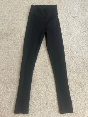Svarta ribbade leggings med hög midja - Snygga svarta leggings med ribbad struktur och hög midja. Perfekta för en trendig och bekväm look. Stretchigt material som sitter skönt och formar sig efter kroppen.