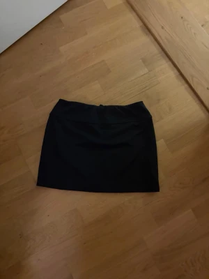 Svart minikjol från Divided - Enkel och stilren svart minikjol från Divided. Kjolen har rak passform och är tillverkad i ett mjukt och stretchigt material som sitter snyggt på kroppen. Perfekt att matcha med en crop top eller oversized tröja.