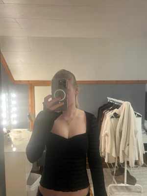 Svart långärmad topp med v-ringning - Snygg svart långärmad topp med v-ringad hals och lätt ribbad struktur. Toppen är figurnära och har en croppad passform med vågig kant nertill. Säljer pga att tröjan inte kommer till användning, bara använt den 1 gång. Köparen står för frakten. Jag står inte för postens slarv.💕