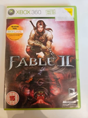 Fable II Xbox 360 spel - Fable II till Xbox 360 är ett action-RPG med fantasytema. Spelet kommer i en grön plastbox med omslag i röd och brun färg, där en hjälte med svärd och pistol syns. Utvecklat av Lionhead Studios och Microsoft Game Studios.