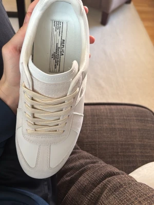 Maison Margiela sneakers - Säljer ett par Maison Margiela  sneakers i vitt läder och mocka med beige snören och klassisk gummisula. 