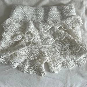 Spets shorts💞 - Superfina cremevita shorts med virkade detaljer och flera lager volanger. Hög midja och elastisk linning för skön passform. Perfekta för varma dagar och ger en romantisk boho-vibe.