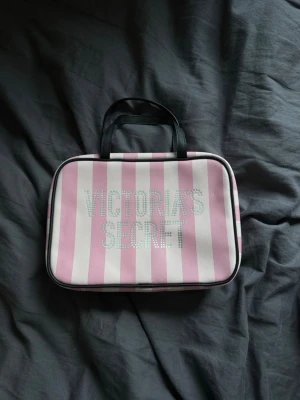 Victoria's Secret neccesär - Säljer en snygg necessär från Victoria's Secret med den klassiska rosa vit randiga designen. 🩷Neccesären har har två stora fack och ett litet perfekt att ha med på resa och ha smink eller andra produkter i tex duschsaker🩷den är rymlig så man får plats med allt smink och väldigt praktisk men också väldigt snygg🌸 tror inte den säljs längre