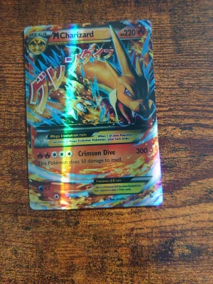 Pokémonkort Mega Charizard EX - Säljer ett samlarkort, Mega Charizard EX från Pokémon. Kortet har en färgstark och glansig design med Charizard i eldig pose och japansk text. Framsidan är holografisk och baksidan har klassiskt Pokémon-motiv. Perfekt för dig som gillar Pokémonkort och samlarobjekt.