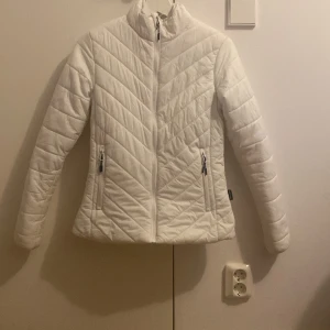 Vit quiltad pufferjacka True North XS - Vit pufferjacka från True North i storlek XS. Jackan är figursydd och har quiltad design med snedställda sömmar framtill, två fickor med dragkedja. Skriv gärna om ni har  frågor eller om fler bilder🤍(dragkedjan är lite sönder, se på sista bilden)