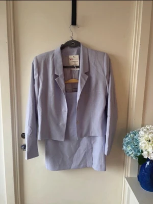 Vintage ljuslila kostymset – kavaj & kjol | 90s / minimalist - Elegant vintage kostymset i ljuslila – kavaj och matchande kjol 💜 Superfin, minimalistisk 90s vibe som funkar perfekt både uppklätt och mer casual (t.ex. med sneakers eller linne). ✔ Kavaj med klassisk krage och tre vita knappar ✔ Figurnära passform ✔ Kjol med slits framtill ✔ Mjukt och bekvämt material Perfekt för vår/sommar, kontor eller en mer stylad vintage look ✨ ✔ Aldrig använd, endast testad ✔ Strl M (passar ca 38/40)