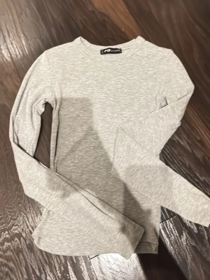 Ljusgrå långärmad topp från New Yorker  - Ljusgrå långärmad topp från new yorker  i mjukt och stretchigt material. Knappt använd och i super skick.