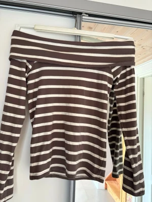 Brun och vit offshoulder topp New Yorker - Säljer en brun och vit randig offshoulder topp från NewYoker. 
