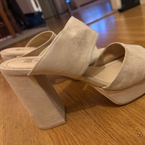 Beige platåsandaler med klack i mocka-look - Snygga beige sandaler från H&M med breda band över foten och hög platåklack. Tillverkade i mockaimitation med öppen tå och chunky klack för en bekväm men snygg look. Sitter skönt runt foten och känns stabila. 