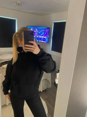 Svart hoodie med ficka framtill - En klassisk svart hoodie med stor ficka framtill och huva. Hoodien har en avslappnad passform och ribbade muddar vid ärmar och midja😊