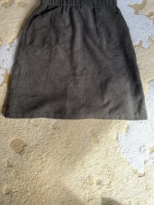 manchesterkjol med fickor - Snygg golivgrön kjol i manchester med två stora fickor framtill och en diskret slits bak. Kjolen har en rak passform och är perfekt för dig som gillar en enkel men trendig stil. Oanvänd