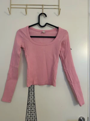 Ljusrosa långärmad topp från Nelly - Ljusrosa långärmad topp med rund halsringning från Nelly i storlek XXS. Modellen är croppad och har en tight passform. 