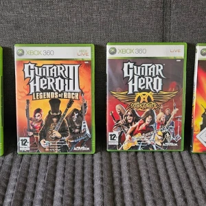 Guitar Hero Xbox 360 spelpaket - 4 Xbox 360-spel: Guitar Hero Legends of Rock och Guitar Hero Aerosmith guitar hero 5 och gyitar hero world tour spelen har färgstarka omslag med rocktema och är i standard gröna plastfodral. Perfekt för dig som gillar musikspel och klassisk rock.