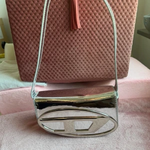 D väska silver - Säljer en riktigt snygg väska från D i metallic silver. Oanvänd och säljes billigt eftersom där är några intryckta streck som syns på bilden.
