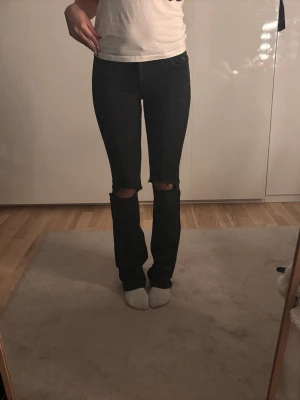Svarta bootcut jeans med slitna knän - Säljer ett par svarta bootcut jeans med slitna hål vid knäna. 