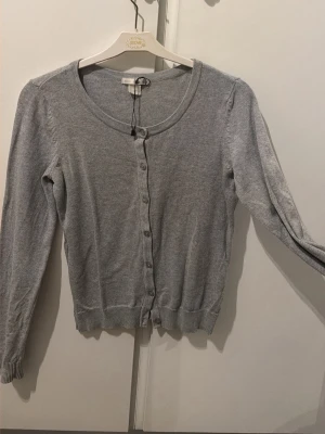 Ljusgrå kofta från H&M BASIC - Ljusgrå tunn kofta från H&M BASIC med rund halsringning och knäppning framtill. 🩶