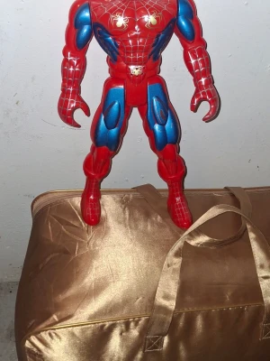 Stor Spiderman-figur i plast - Säljer en stor Spiderman-figur i hård plast med klassisk röd och blå design samt spindelmotiv på bröstet. Perfekt som dekoration eller leksak för Marvel-fans. Figuren har tydliga muskeldetaljer och är riktigt iögonfallande.