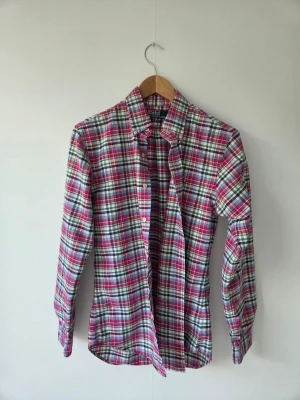Rutig skjorta från Polo Ralph Lauren, stl s - Färgglad rutig skjorta från Polo Ralph Lauren i slim fit-modell. Skjortan har långa ärmar, klassisk krage och knäppning framtill. Broderad logga på bröstet och tillverkad i mjuk bomull. Perfekt för en avslappnad men stilsäker look.