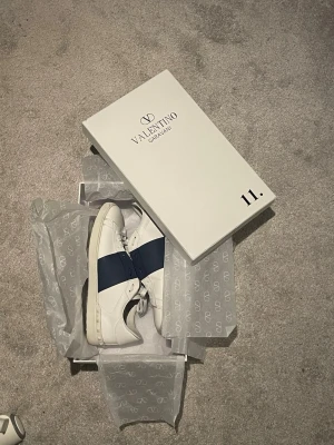 Valentino Open   - Ett par riktigt schysta Valentino Open i storlek 45. Skorna är väl omhändertagna och använts med försiktighet. Använda minimalt. Visst, lite tecken på användning men ingenting som stör utseendet eller skornas skönhet. Ingår: Skor, Valentino Shoebag, Valentino Bag, litet Valentino brev. Skorna är vitare i verkligheten kan jag säkerställa. Dessa skor passar perfekt och är otroligt snygga inför sommaren. Köp dessa så får du äkta istället för dåliga kopior :) Fraktar snabbt!!! Hör av dig vid frågor!