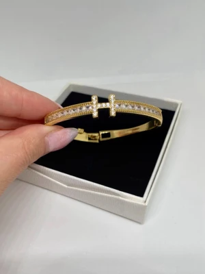 Guldigt armband med gnistrande stenar - Guld färgad armband med stenar, gjord av rostfri stål från Swedora. Man knäpper fast den så den sitter säkert runt handleden (kolla andra bilden) väldigt bra skick och knappt använd, skriv om du har frågor🌸