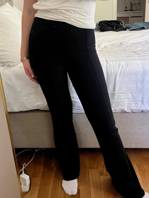 Svarta byxor med utsvängda ben - Säljer ett par svarta leggings med ribbad struktur och utsvängda ben. De har hög midja och är stretchiga för en bekväm passform. Perfekta till en avslappnad eller trendig look. Pris kan alltid diskuteras 🥰