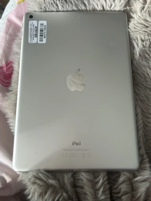 Apple iPad silver, modell A1822 - Generation 5/6, de vita prickarna är luftbubblor som inte gick bort när skärmen byttes men dom är inget man märker💗Säljer en silverfärgad Apple iPad modell A1822 med stilren design och rundade hörn. Baksidan är i aluminium med Apple-loggan i mitten. Perfekt för surf, spel och appar. Laddas via lightning-kontakt och har kamera i hörnet.