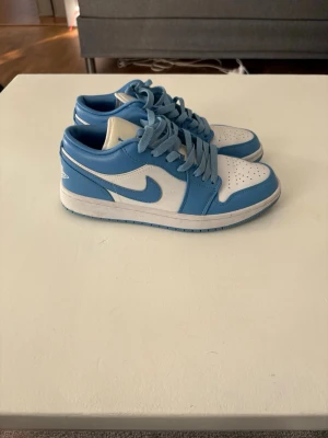 Jordan 1 Low UNC  - Snygga Jordan 1 Low sneakers i klassisk UNC-färg med blå och vita paneler, storlek 41. Passar till streetwear och mer casual outfits. Skorna är i mycket bra skick, använda cirka 10-15 gånger.