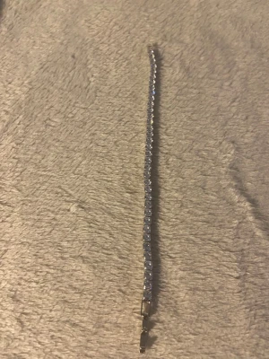Silverfärgat armband med pärlor - Ett stilrent armband i silverfärg med små, glittrande pärlor i rad. Armbandet har en klassisk och tunn design som passar perfekt till din outfit. Låset är diskret och smidigt. Perfekt accessoar för dig som gillar enkel men snygg stil.