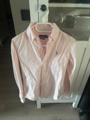 Ralph Lauren Skjorta - Snygg rosa och vit randig skjorta från Polo Ralph Lauren i modellen Custom Fit. Skjortan har klassisk krage, knappar framtill och broderad logga på bröstet. Perfekt för en stilren och fräsch look.
