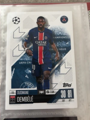 PSG fotbollssamlarbilder Topps - Två samlarkort från Topps med PSG-spelare, en i blå hemmatröja och en i gul målvaktsdräkt. Korten har klubbmärke, spelarinfo och Champions League-design. Perfekt för dig som gillar fotboll och samlar på sportkort.