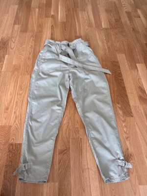 Byxor H&M stl 38 - Ljusgröna byxor från H&M i storlek 38.  De har bälte/snörning och fickor.  Mycket bra skick. 