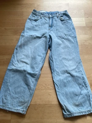 Ljusblåa baggy jeans - Säljer ett par ljusblåa baggy jeans med rak passform och breda ben. Jeansen har klassisk femficksdesign och är tillverkade i denim. 