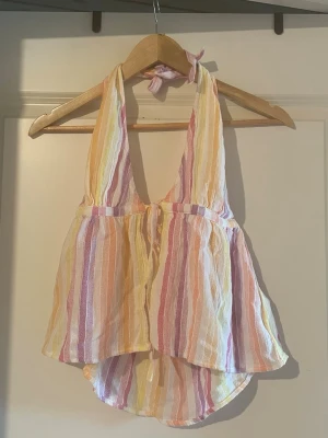 Randig halter topp i pastell - Söt ärmlös topp med pastellfärgade ränder i gult, rosa, lila och vitt. Toppen knyts vid nacken och kan också justeras vid bysten. Har aldrig använts! 💕