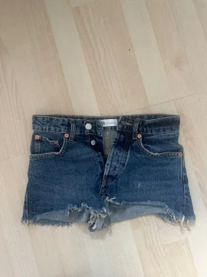 Blå jeansshorts med fransig kant - Säljer ett par blå jeansshorts med fransar från Zara. Endast använda några få gånger så de är som nya! Perfekta till sommaren☺️