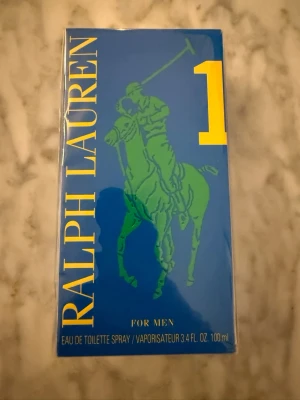 Ralph Lauren Big Pony 1 EdT 100ml - Fräsch herrparfym från Ralph Lauren, Big Pony 1, i en blå rektangulär kartong med grön polospelare och gula detaljer. Eau de toilette spray, 100 ml. Perfekt för dig som gillar sportiga och energiska dofter.