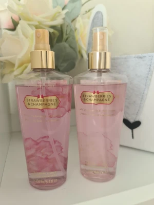 Strawberries & Champagne Body Mist - Fräsch body mist från Victoria's Secret i doften Strawberries & Champagne. Flaskan är genomskinlig med rosa vätska och har guldfärgad spraykork. Volymen är 250 ml. Perfekt för dig som gillar söta och fruktiga dofter. Den till vänster luktar väldigt gott och den till höger har bleknat lite och luktar sämre. Säljer nu av min vintage kollektion. Perfekt för samlare. Eftersom dofterna är vintage kan lukten skilja sig markant från nya, och köps därmed på eget bevåg.